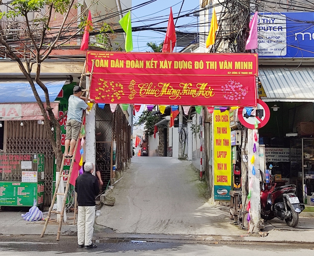 Người dân tranh thủ treo cờ, trang trí cổng văn hóa ở khu dân cư.